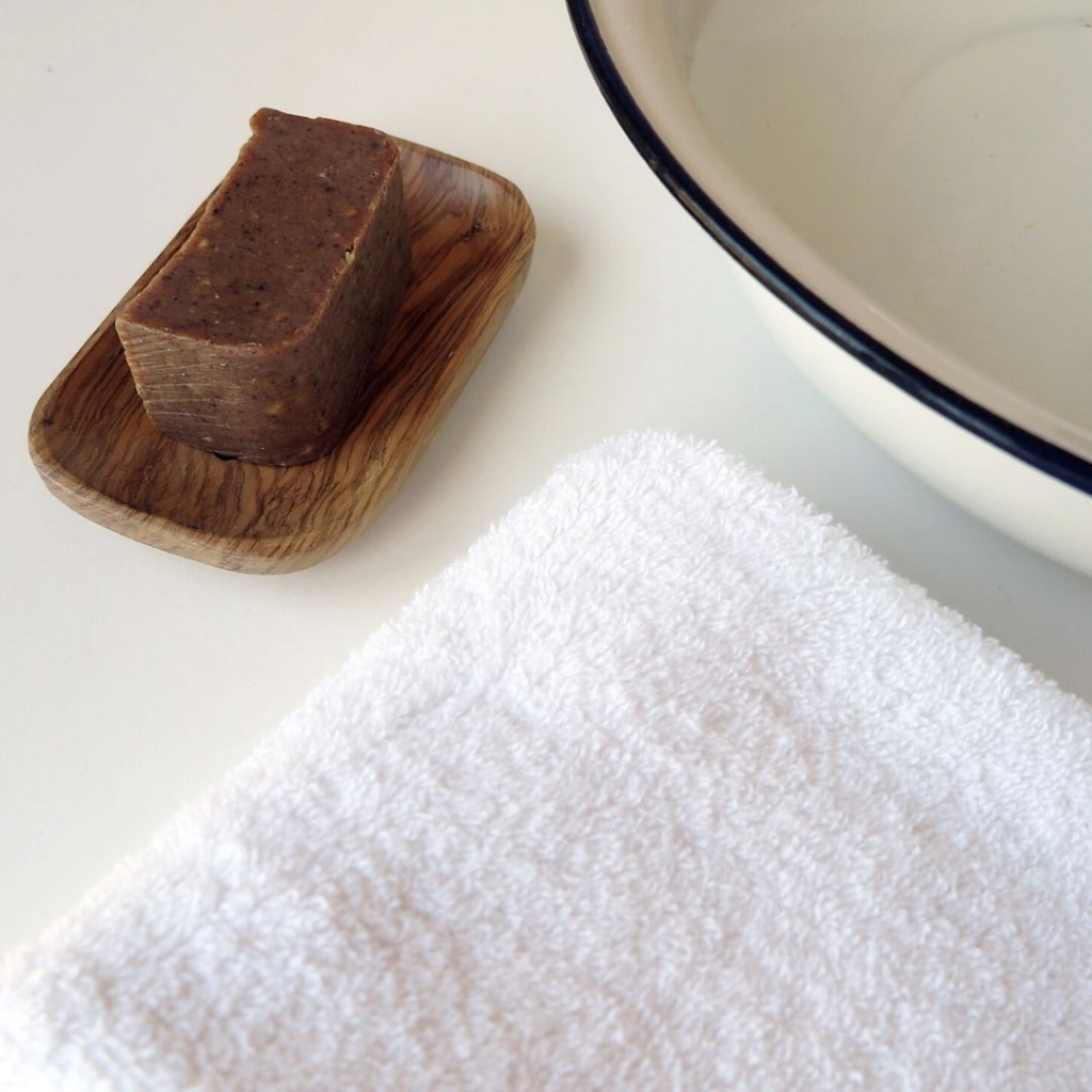 Imagen de un pedazo de Jabón Exfoliante Ylang Ylang y Canela Bio de Arboleda Cosmética Natural sobre una jabonera de madera.