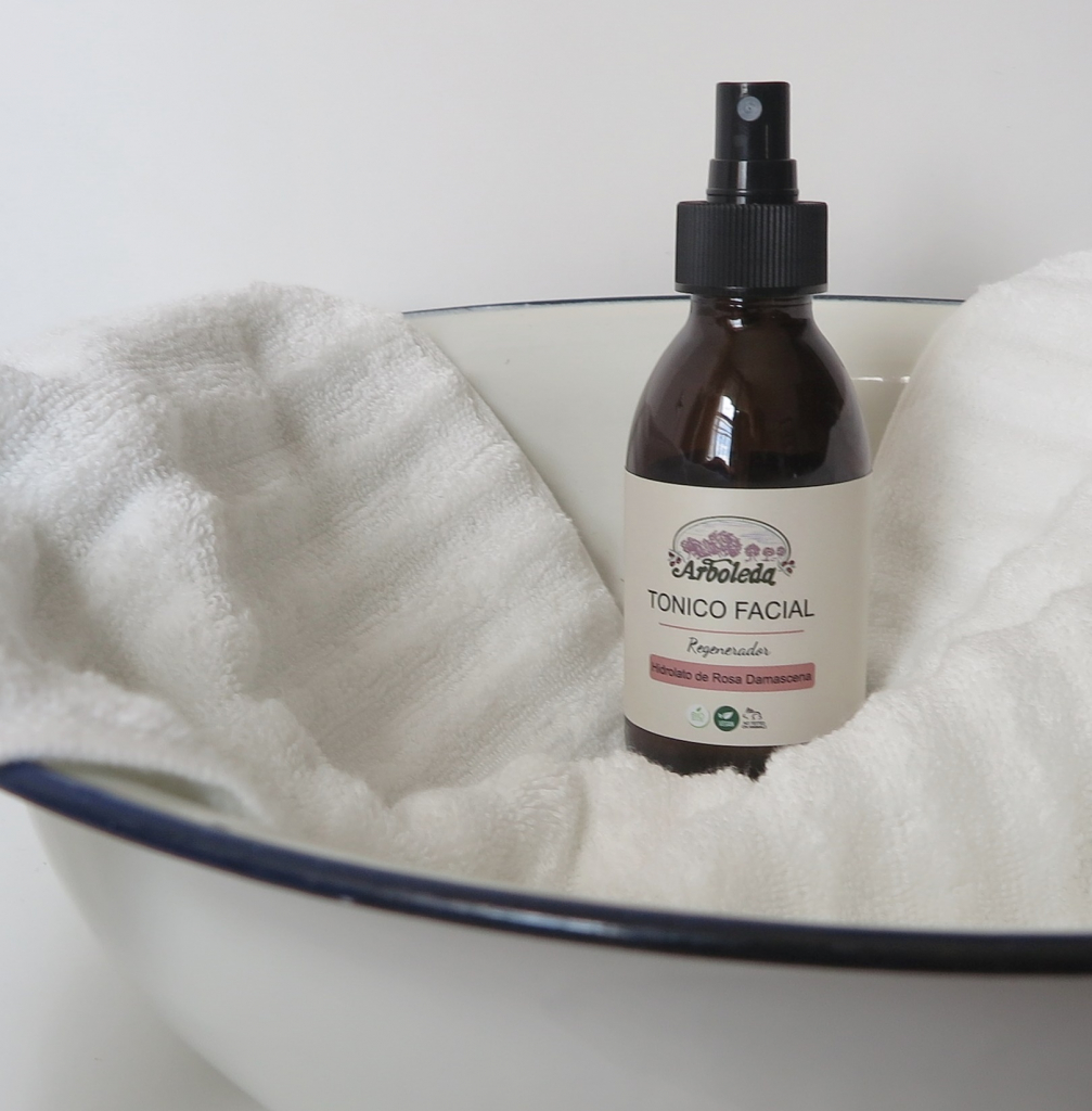 Imagen de un frasco de Tónico Facial Regenerador efecto anti-edad de Arboleda Cosmética Natural sobre una toalla en una palangana.